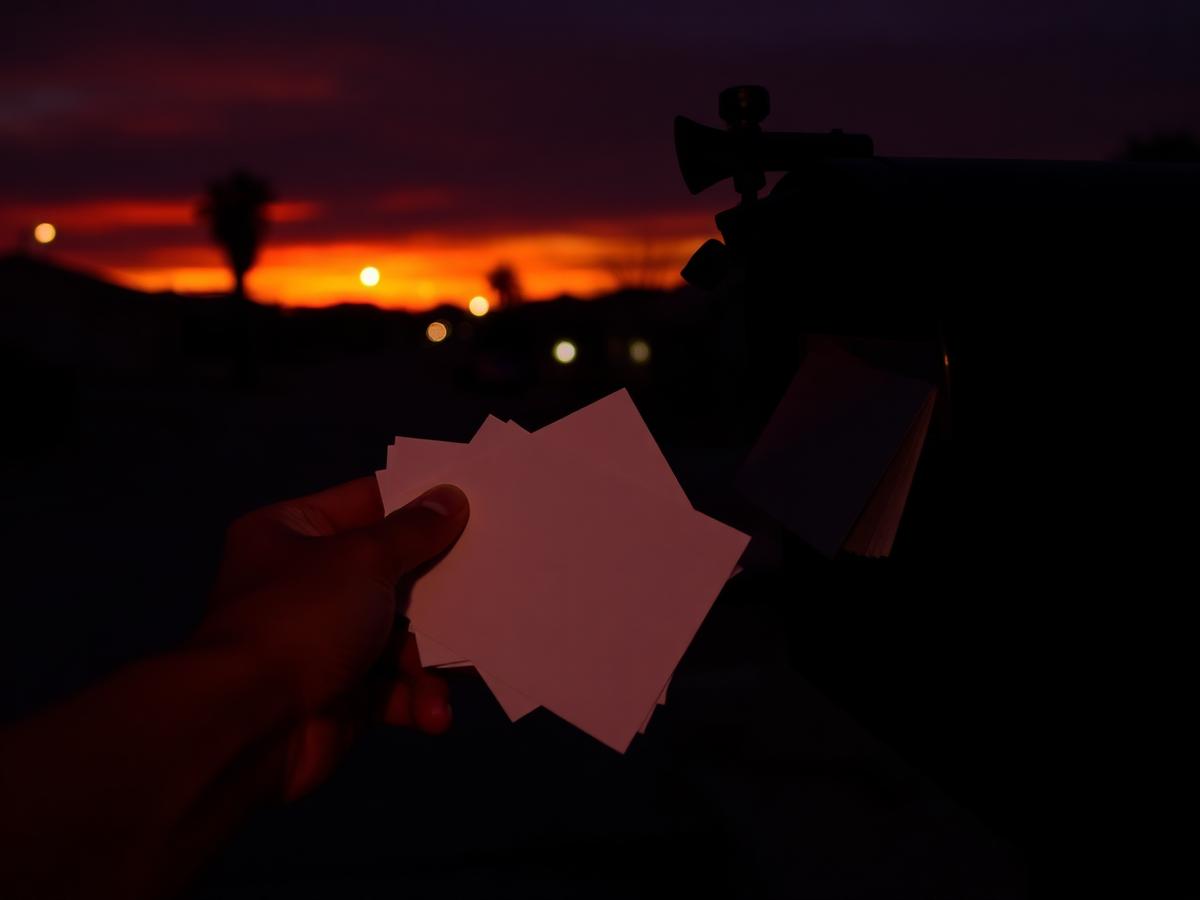 Hand pulling mail from a residential mailbox at desert sunset