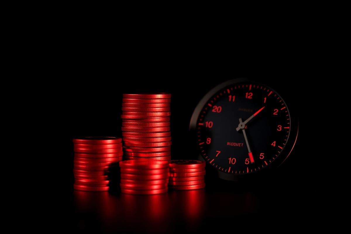 Stacks of red coins beside a dark dial representing ad budget pacing