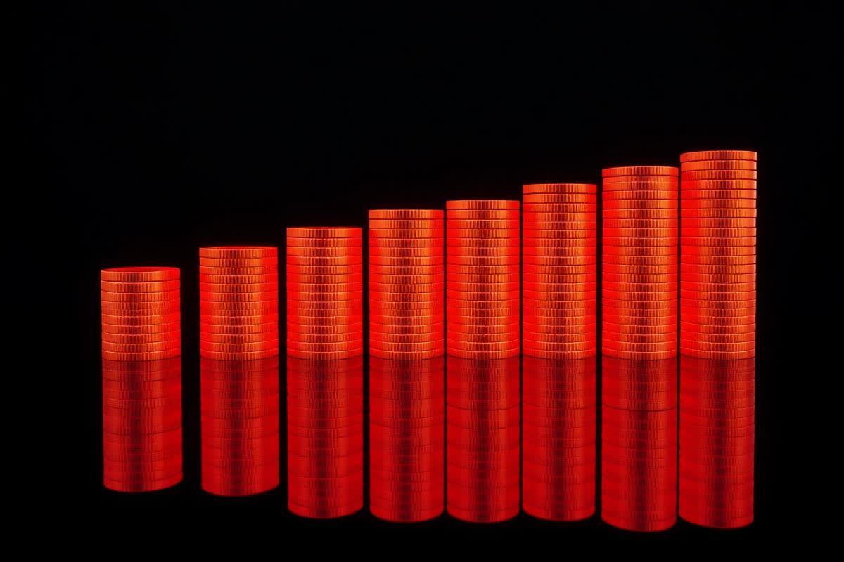 Rising stacks of glowing orange coins representing ad budget allocation