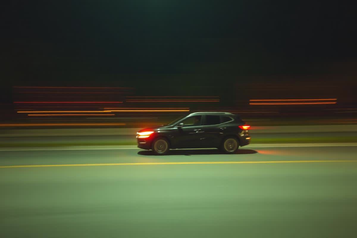 Vehicle moving at speed on a night road with light streaks